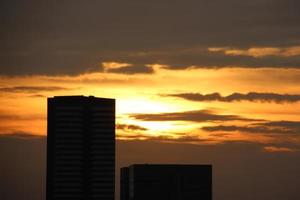 mörk blå moln med vit ljus Sol uppsättning himmel bakgrund och stad ljus midnatt kväll tid foto