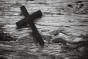 en trä- kristen korsa krucifix på en grunge styrelse bakgrund. trä- kristen korsa på grå tabell mot suddig lampor, Plats för text. foto