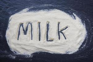 mjölk pulver på mörk bakgrund - pulveriserad mjölk text topp se , mat friska kropp från protein eller för bebis begrepp foto