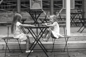 liten flickor Sammanträde på utomhus dining område foto