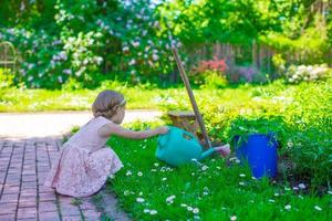 liten flicka med blommor i de trädgård foto