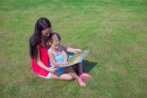 mor och dotter läsning utomhus foto