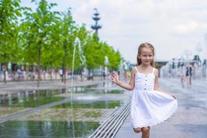 liten flicka spelar på en vatten fontän foto