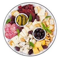 antipasto tallrik med basturma, salami, blå ost, nötter, ättiksgurka och oliver på en isolerat vit bakgrund. topp se, över huvudet foto