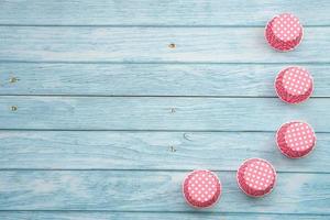 rosa polka punkt muffin fall på blå trä- golv. material eller kök Utrustning för bageri. foto