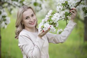 skön kvinna i en blomning trädgård, leende, njuter liv foto