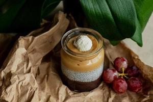 hemlagad pudding med granola, kiwi, vindruvor, kokos, blomma blad bakgrund foto