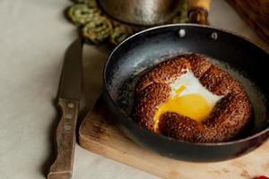 turkiska frukost, krypterade ägg i en simit bulle i en fräsning panorera, kaffe i en turk, färsk bröd foto