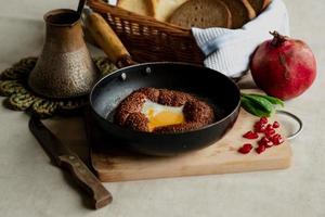 turkiska frukost, krypterade ägg i en simit bulle i en fräsning panorera, kaffe i en turk, färsk bröd foto