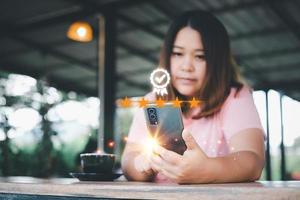 kund erfarenhet begrepp. asiatisk kvinnor använder sig av en smartphone Sammanträde i en kaffe affär som visar ett excellent femstjärnigt betyg. foto