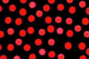 ofokuserad abstrakt röd bokeh på svart bakgrund. defocused och suddig många runda ljus foto