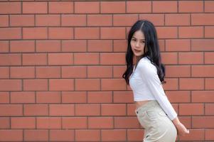 porträtt av hipsterflicka på tegelväggsbakgrund, vacker asiatisk kvinna poserar för att ta ett foto, kawaii-stil foto