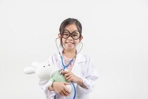 Asien liten flicka spelar läkare isolerat på vit foto