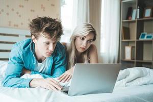 lyckliga par som använder bärbar dator på sängen