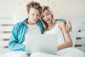 lyckliga par som använder bärbar dator på sängen foto