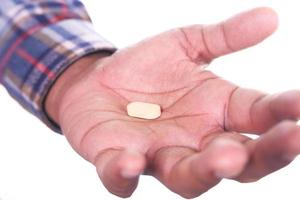 närbild på manhand som håller ett piller isolerad på vit bakgrund foto