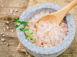 himalayan rosa salt i mortel med timjan på hampasäckbakgrund. himalayansalt som vanligtvis används vid matlagning och för badprodukter såsom badsalt. foto