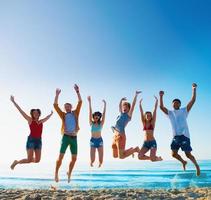 Lycklig leende vänner Hoppar på de strand foto