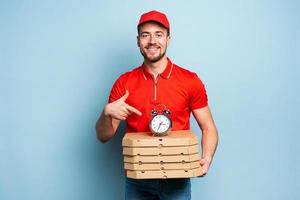 deliveryman är punktlig till leverera snabbt pizzor. cyan bakgrund foto