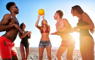 grupp av vänner spelar på strand volley på de strand foto