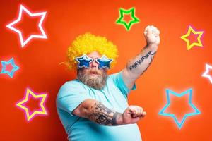 fett man med skägg, tatueringar och solglasögon danser musik på en disko foto