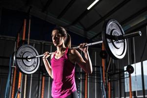 atletisk flicka Arbetar ut på de Gym med en skivstång foto