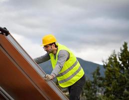 man Arbetar på förnybar energi systemet med sol- panel för varm vatten foto