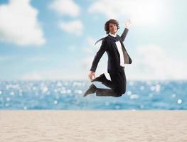 affärsman hoppar på de sand. begrepp av semester foto