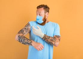rädd man med skägg, tatuering och mask för covid-19 är redo för de virus vaccin foto