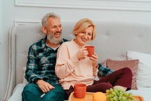 Make och fru ha frukost på de säng med kaffe och frukt foto