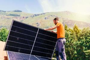 arbetare montera energi systemet med sol- panel för elektricitet och varm vatten foto