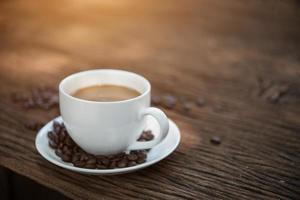 kaffekopp och kaffebönor på träbord foto