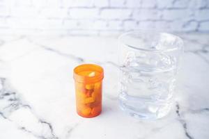 närbild av piller och ett glas vatten foto