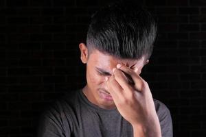 ung man med huvudvärk isolerad på svart bakgrund foto
