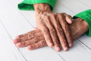 äldre persons händer som isoleras på det vita bordet foto