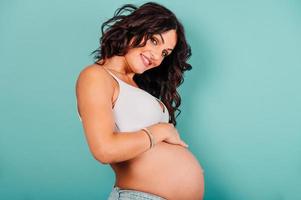 gravid Lycklig kvinna förväntar sig en barn smeker henne mage foto