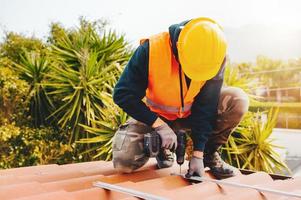 teknisk arbetstagare Arbetar med borra på de tak av en hus foto