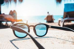 solglasögon av en turist på en deckchair på en strand foto