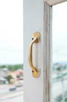 gyllene rostfri stål årgång stil hantera på målad trä- vit fönster, möbel handtag foto