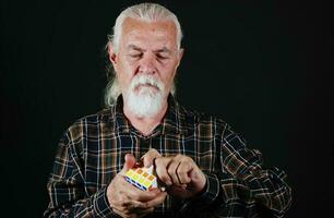 gammal man är spelar med rubiks kub spel foto