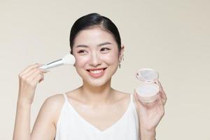pulver rodna kvinna asiatisk utseende leende och smink borsta foto