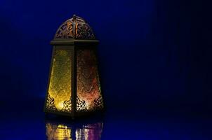 lykta sätter på tabell med mörk blå bakgrund för de muslim fest av de helig månad av ramadan kareem. foto