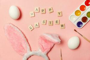 inskrift Lycklig påsk brev ägg färgrik målarfärger och kanin öron isolerat på trendig rosa bakgrund foto