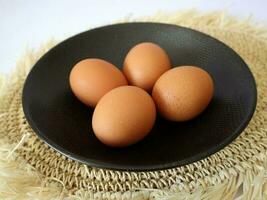 fyra kyckling ägg i en svart tallrik foto