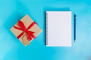 topp se brun gåva låda och anteckningsbok papper för ny år på blå pastell Färg. foto