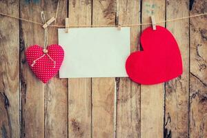 två hjärta hängande och papper på klädstreck och rep med trä- bakgrund foto