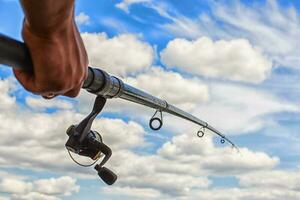 fiske stång på en blå himmel bakgrund i en mannens hand foto