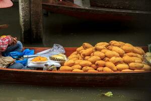 båtar försäljning frukt - mogen mango - i damnoen saduak flytande marknadsföra är en populär turist destination den där européer och kinesisk tycka om till resa med de traditionell sätt av liv av de bybor. foto
