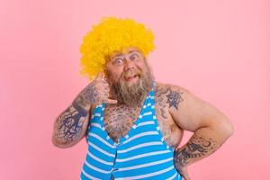 Lycklig man med gul peruk och baddräkt är redo till de sommar foto