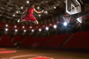 basketboll spel med en hög hoppa spelare till göra en slam dunka till de korg foto
